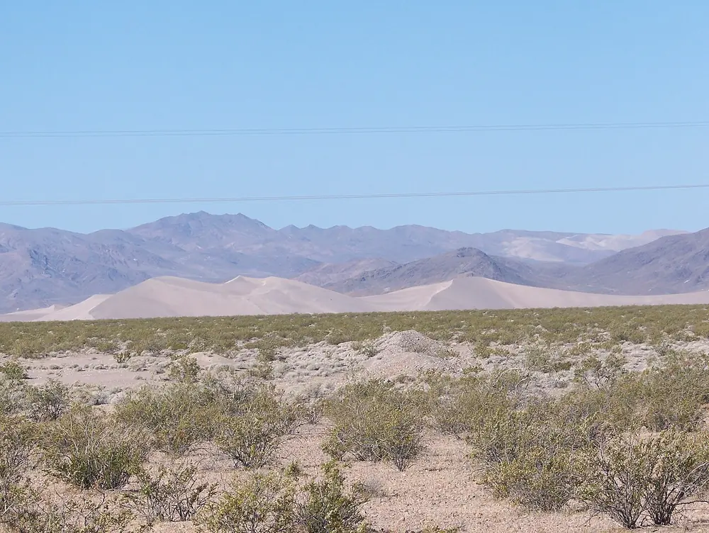 Big Dune rising from the open Amargosa Desert with mountains behind it.